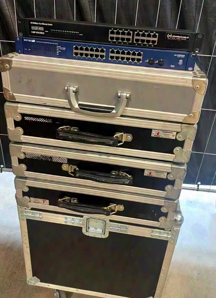 Diverse Netzwerk-Switches, darunter Modelle von Netgear und 3Com. Einige Geräte befinden sich in Flightcases.